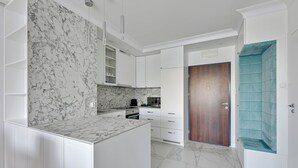 Een moderne keuken met witte kastjes, een marmeren spatwand en een houten deur.