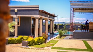 Un edificio con piscina, columnas y un área techada con una escalera.