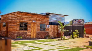 Una cabaña rústica de troncos con un letrero que dice 'KITCHEN', un letrero de 'SALE' y un letrero que indica 'LIFESTYLE & SWIMMING POOL'.