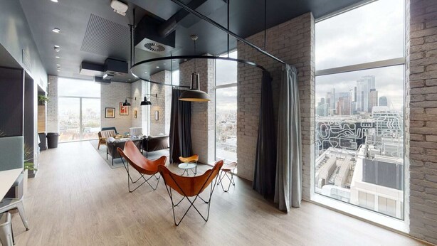 A modern office space with a large window offering a city view, leather chairs, and a minimalist design. - Student Only Shoreditch (London)