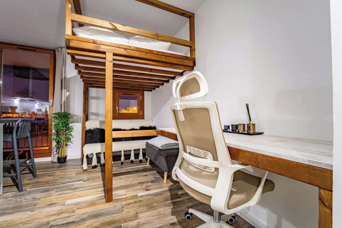 Une chambre avec un lit superposé, un bureau, une chaise et une plante en pot.