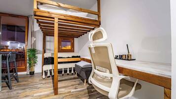 Une chambre avec un lit superposé, un bureau, une chaise et une plante en pot.