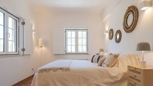 A bedroom with a bed, bedside tables, a window, and wall-mounted decor. - Ground floor apartment - Villa Natura Bliss (Alcácer do Sal)