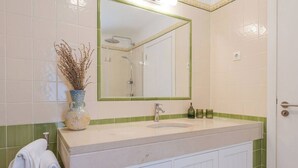 A bathroom with a sink, mirror, and shower. - Ground floor apartment - Villa Natura Bliss (Alcácer do Sal)