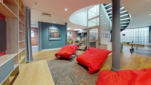 A modern interior with a spiral staircase, red bean bags, and a brick wall. - Student Only Will Wyatt Court (London)
