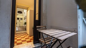 A narrow hallway with a checkered floor leading to a room with a door. - Palazzo Bicocca Rooms (Catania)