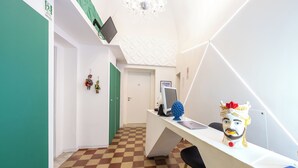 A reception desk with a checkered floor, a chandelier, and a decorative headpiece. - Palazzo Bicocca Rooms (Catania)