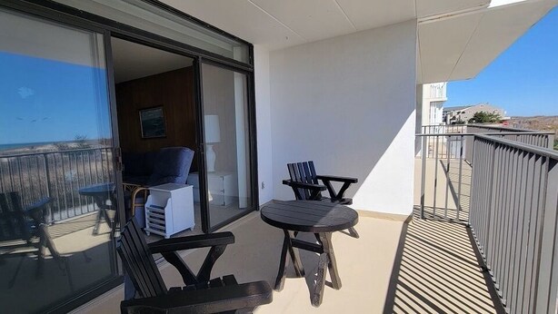 Un balcon avec vue sur la mer, un canapé et deux fauteuils.