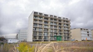 Un immeuble à plusieurs étages, doté d’une façade uniforme, de balcons et d’un monte-charge vert utilisé pour les travaux de construction.