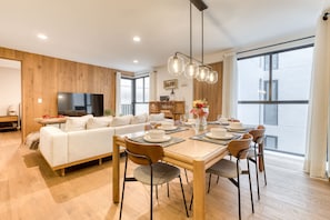 A modern living room with a dining area, wooden walls, a flat-screen TV, and large windows. - Av Michoacan 21 403 in Ciudad de M Xico (Mexico City)