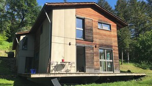 A two-story house with a wooden exterior, large windows, and a balcony. - A bed and breakfast in the woods (Pommiers)