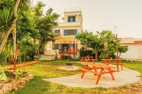 A building with a patio area featuring picnic tables and a barbecue grill.