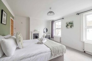 A bedroom with a bed, a fireplace, a mirror, and a window.