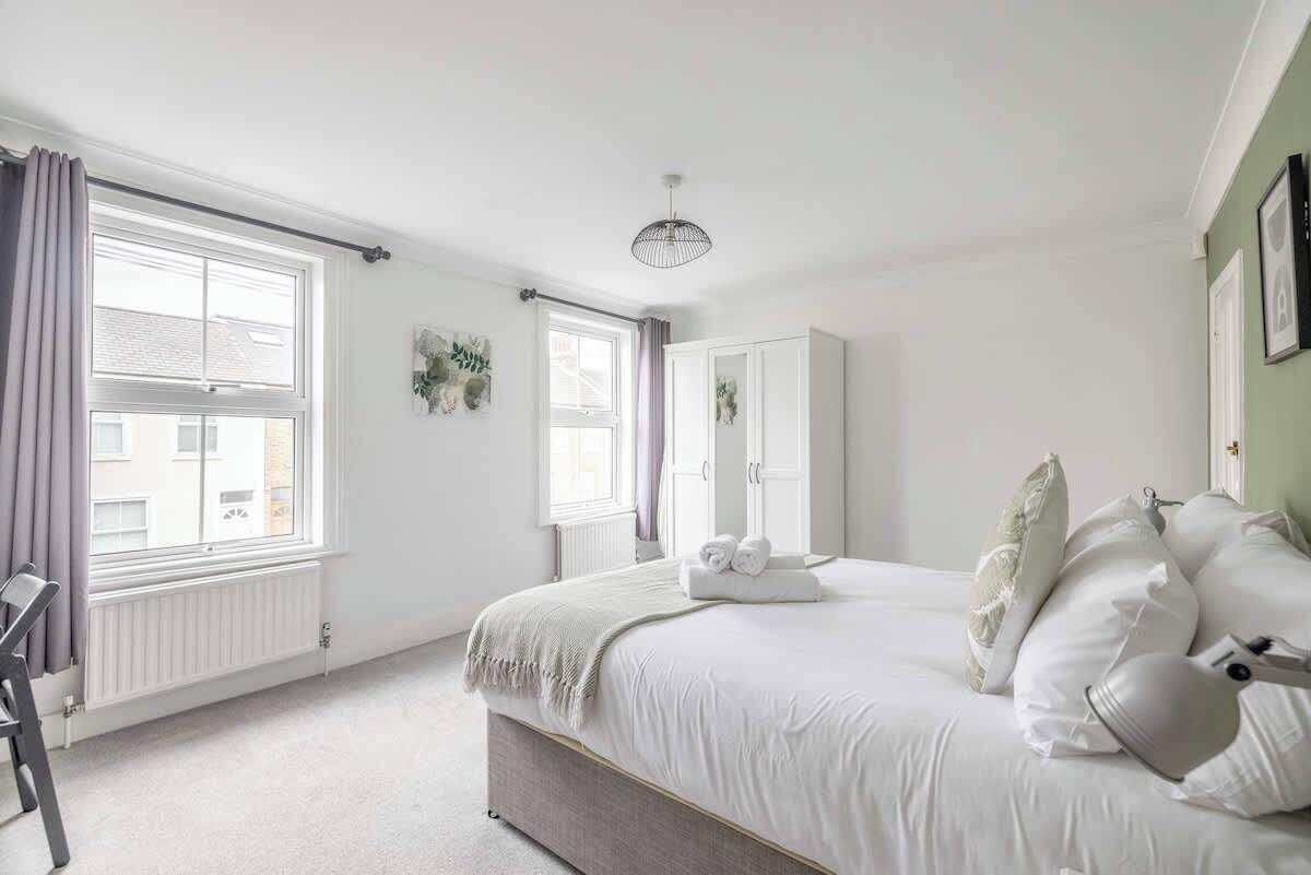 A bedroom with a bed, a chair, a radiator, and a window.