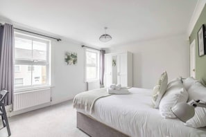 A bedroom with a bed, a chair, a radiator, and a window. - Charming 2 Bed House in Windsor - By Tempstay (Windsor)