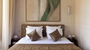 A neatly made bed with a patterned headboard, a large abstract painting above it, and a nightstand with a lamp and a vase. - Palais Bourbon Hotel - Room 34 - 2P - Invalides (Paris)