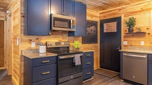 A modern kitchen with dark cabinets, a microwave, a stove, and a dishwasher. - Fall on Whitefish Bay | Private Beach, Fireplace (Paradise)