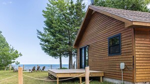 A wooden cabin with a deck, a view of the sea, and a few chairs. - Fall on Whitefish Bay | Private Beach, Fireplace (Paradise)