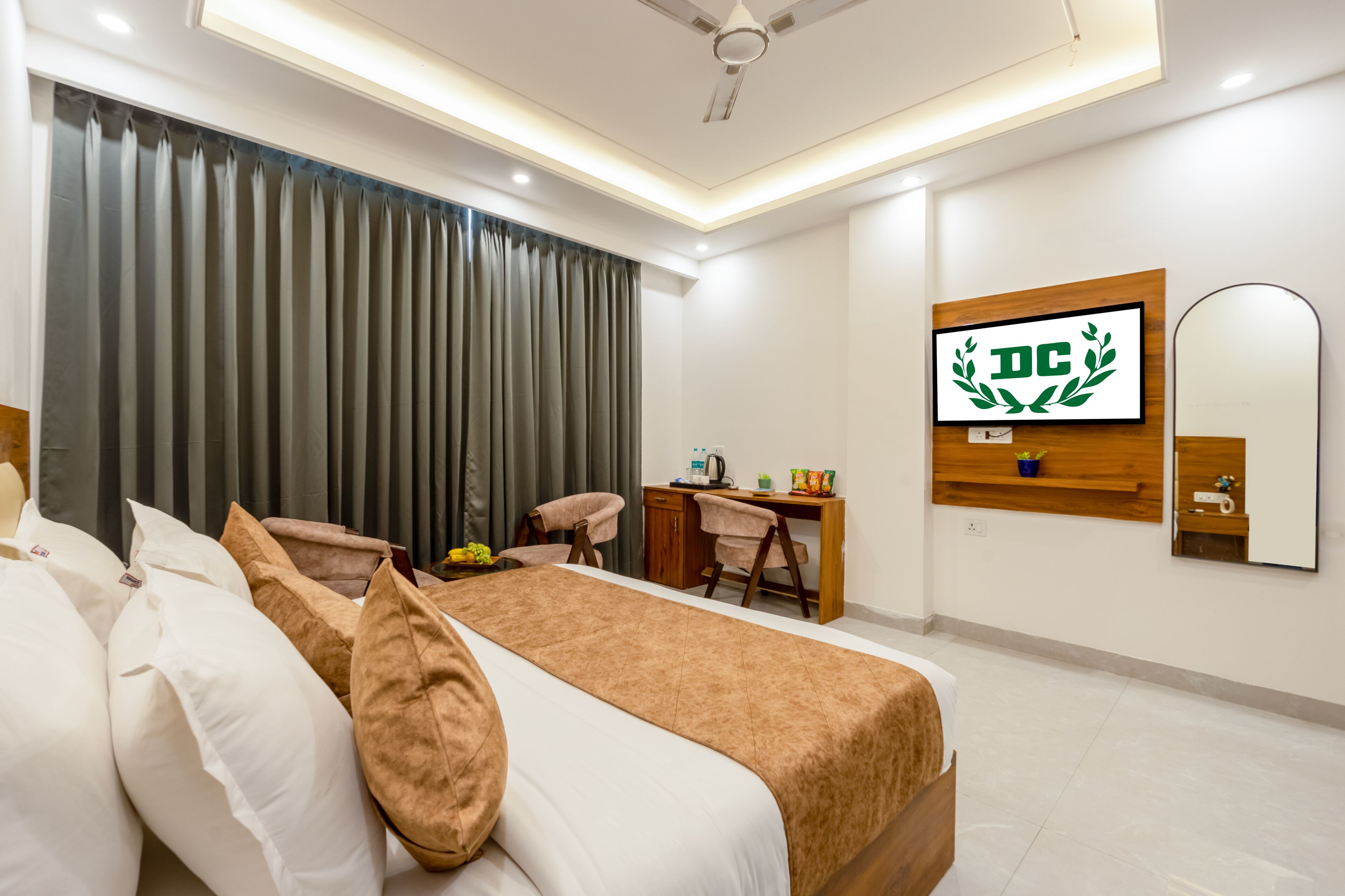 A hotel room with a bed, a desk, a chair, a TV, and a mirror.