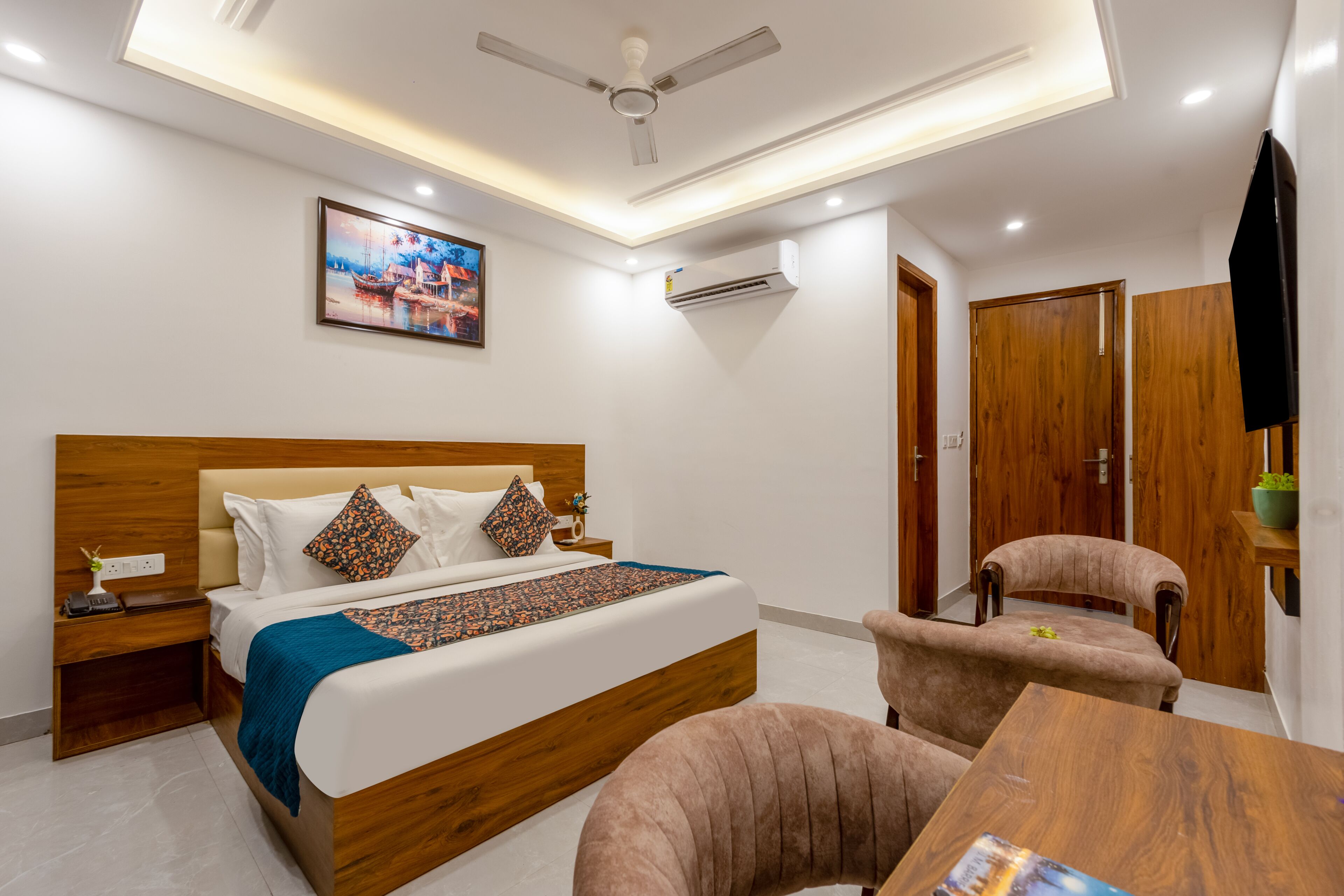A modern hotel room with a bed, bedside table, chair, and a small table.