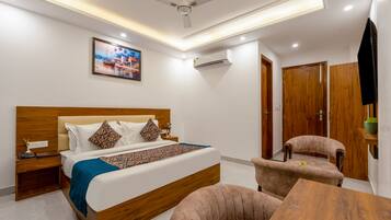 A modern hotel room with a bed, bedside table, chair, and a small table.