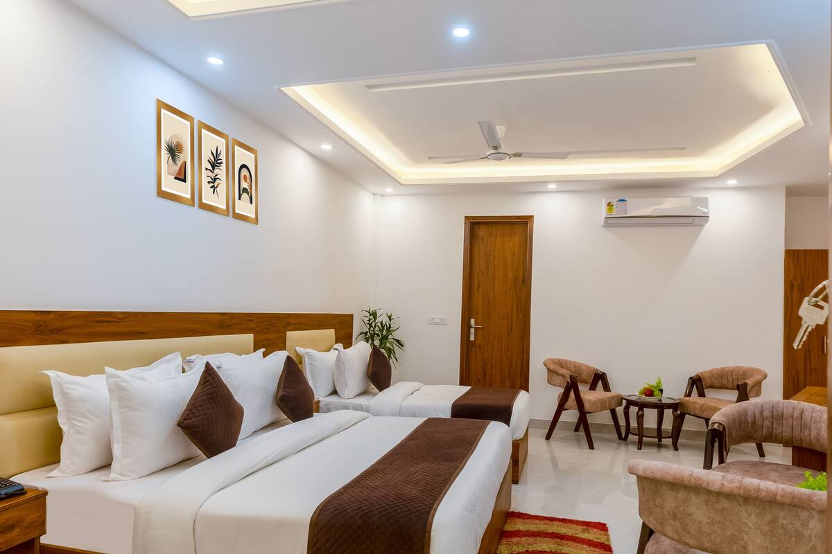 Una habitación de hotel moderna con una cama grande, un escritorio, dos sillas, un ventilador de techo y un equipo de aire acondicionado.