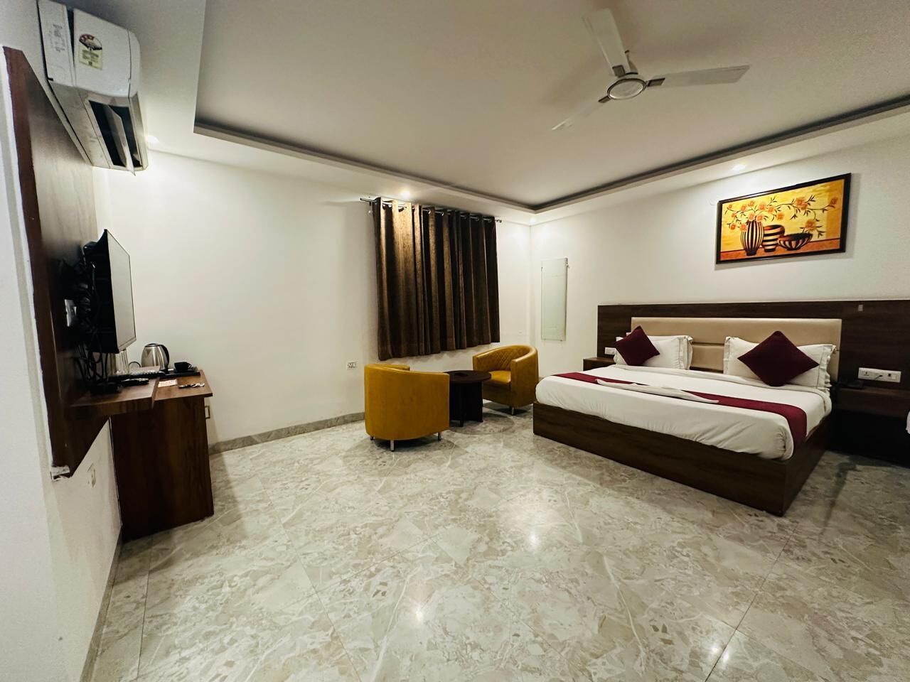 A hotel room with a bed, a desk with a computer, a chair, and a TV.