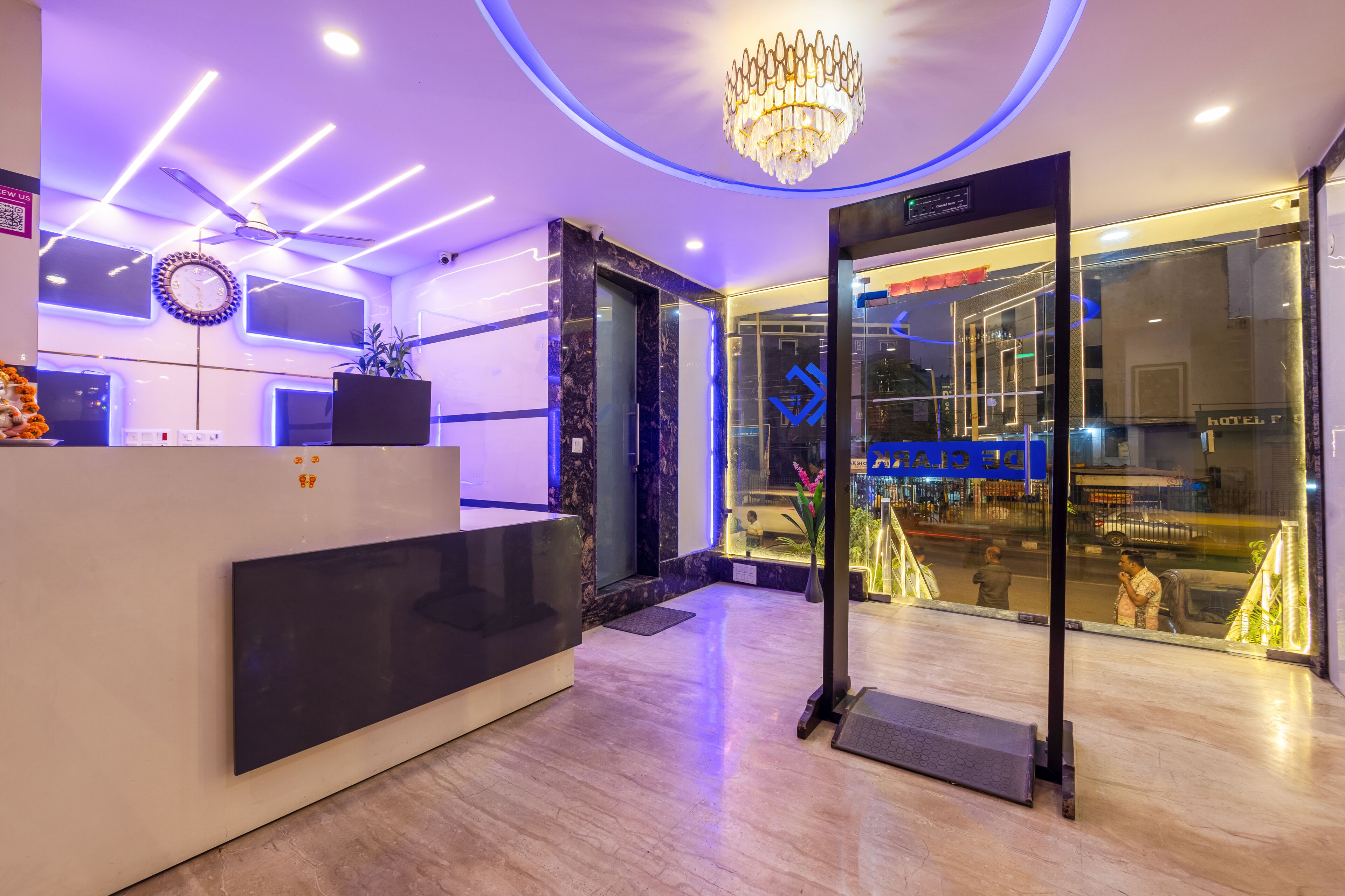 Ein Hotel-Empfangsbereich mit modernem Design, darunter eine Rezeption, eine digitale Uhr und eine Chandelier.