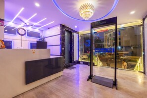 A hotel reception area with a modern design, including a reception desk, a digital clock, and a chandelier. - HOTEL THE CLARK (New Delhi)