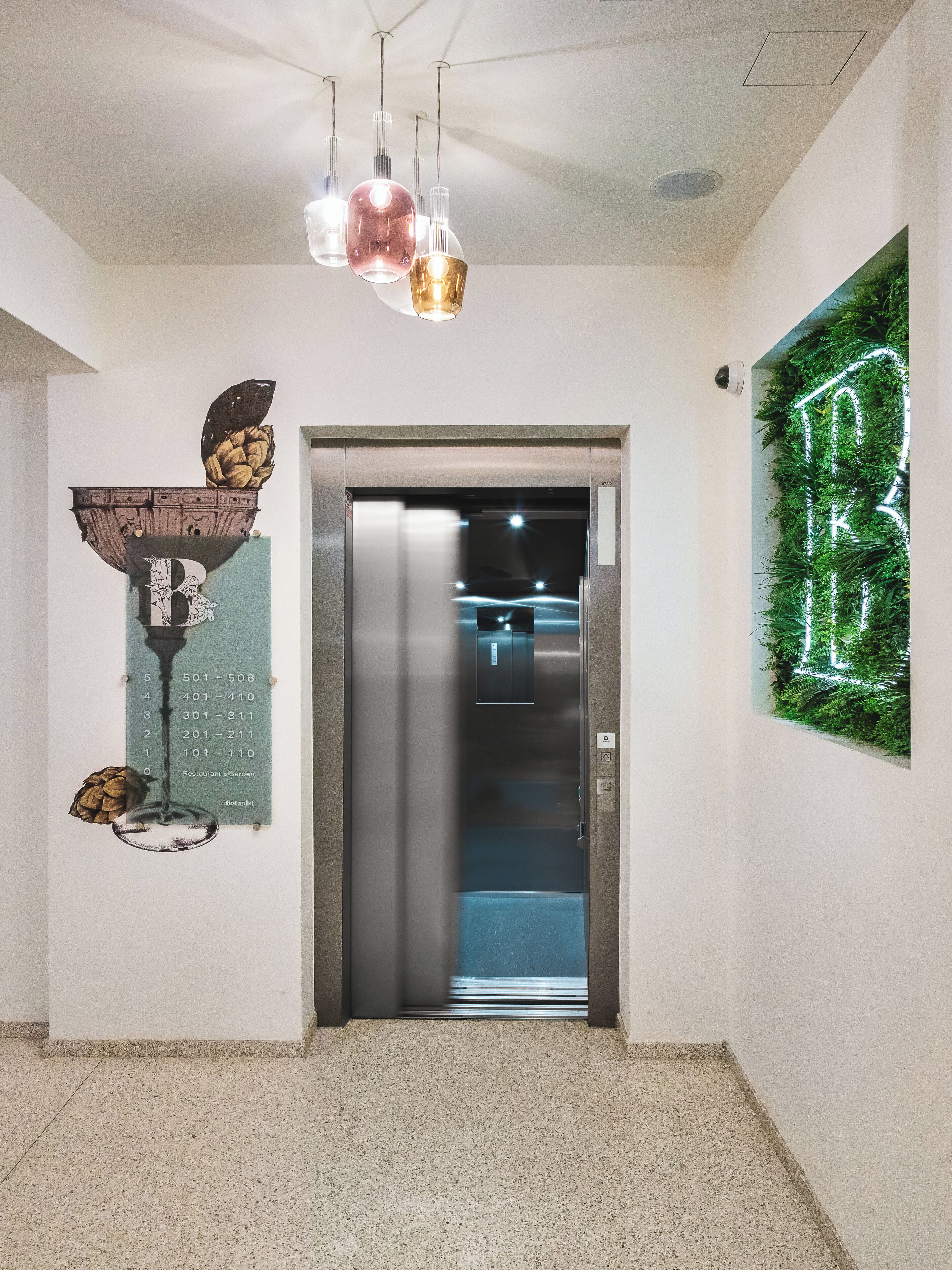 An elevator with a digital display, a wall-mounted sign with a number, and a ceiling light fixture.