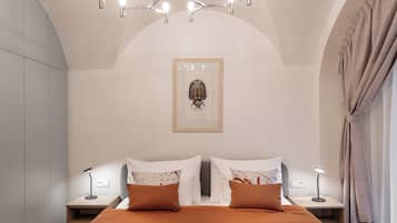 Un dormitorio moderno con una cama grande, dos mesitas de noche, una lámpara de techo hexagonal original y una obra de arte enmarcada en la pared.