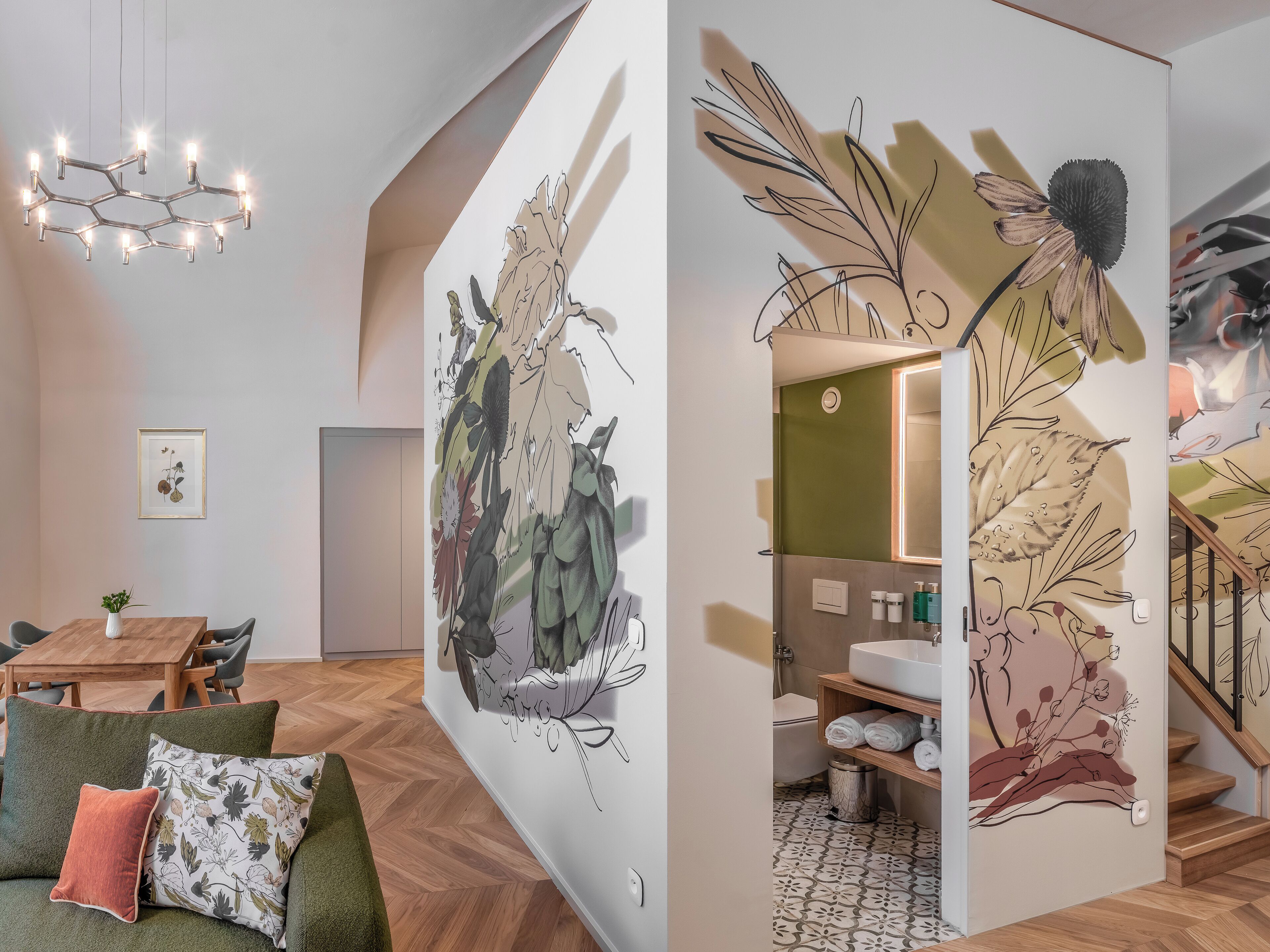 A modern interior with a dining area, a staircase, and a bathroom with a large floral mural.