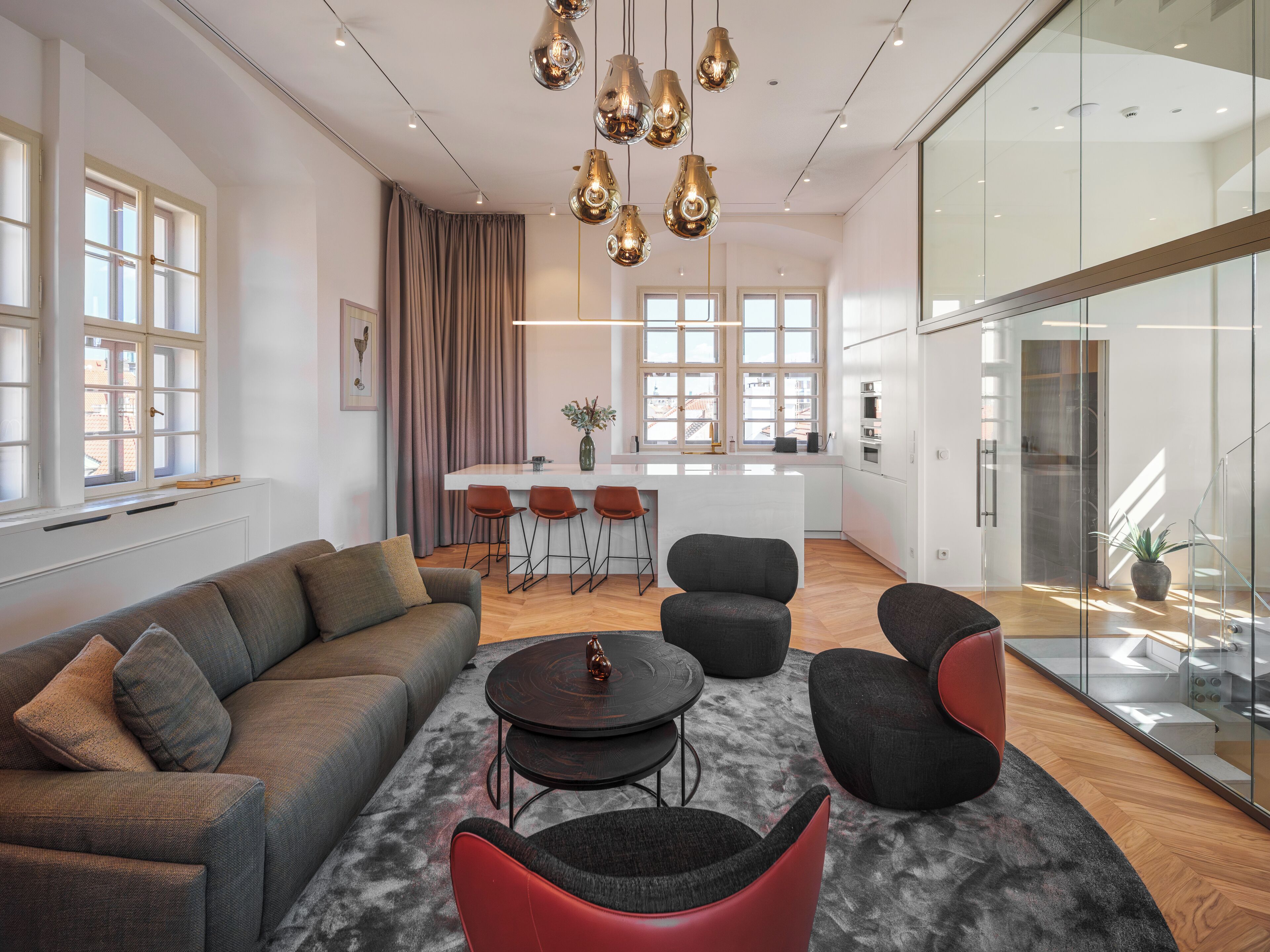 A modern living room with a sofa, chairs, a coffee table, and a kitchen area with a bar.