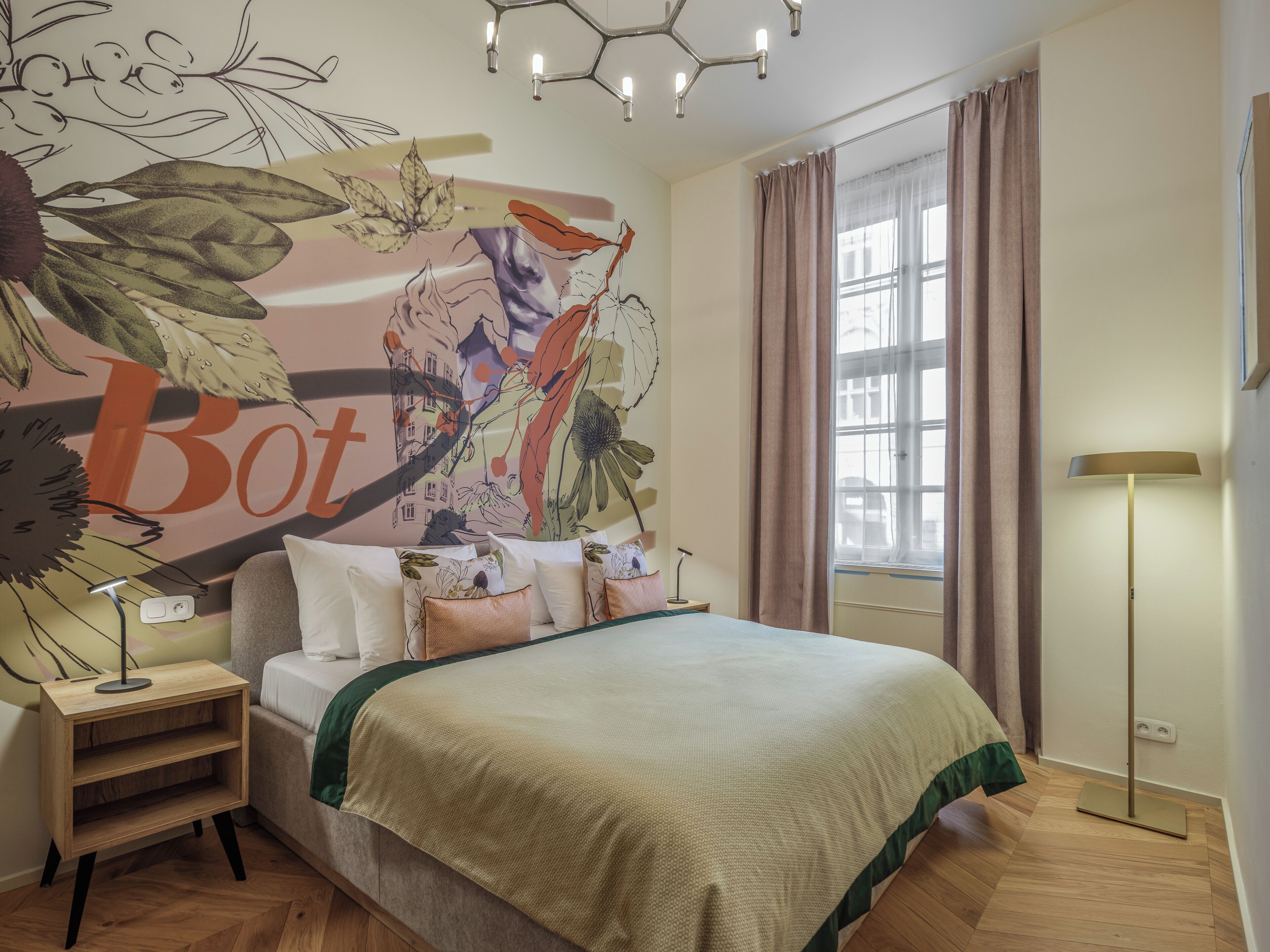 Un dormitorio con una cama grande, una mesita de noche, una lámpara, una ventana con cortinas y un mural en la pared.