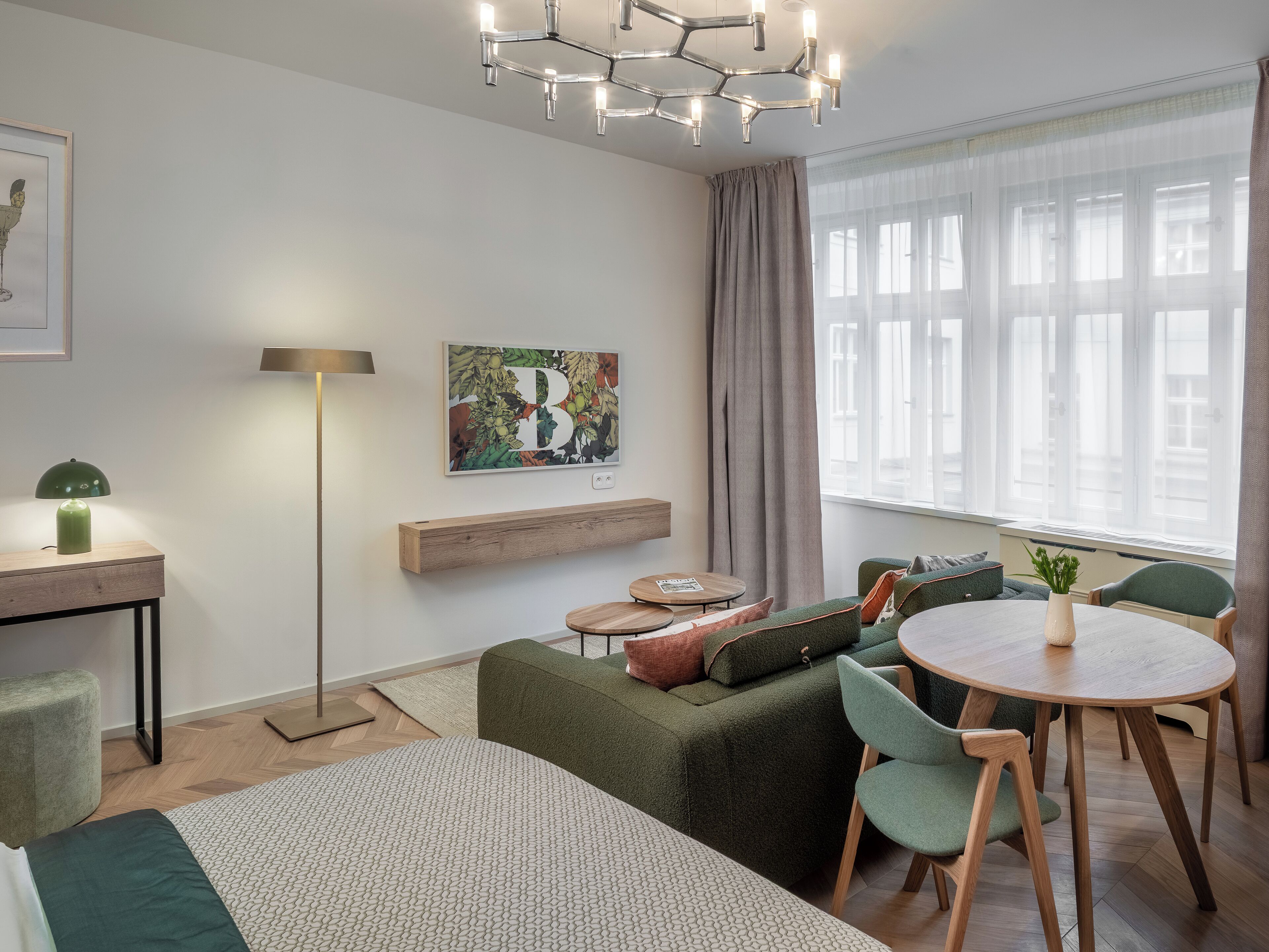 Una stanza moderna e luminosa con un divano verde, un tavolo rotondo e un quadro appeso al muro.