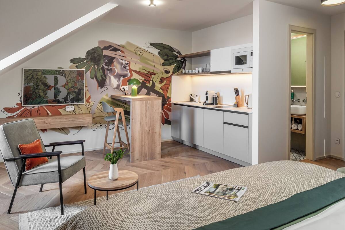 A modern loft apartment with a kitchen, dining area, and a sleeping area.