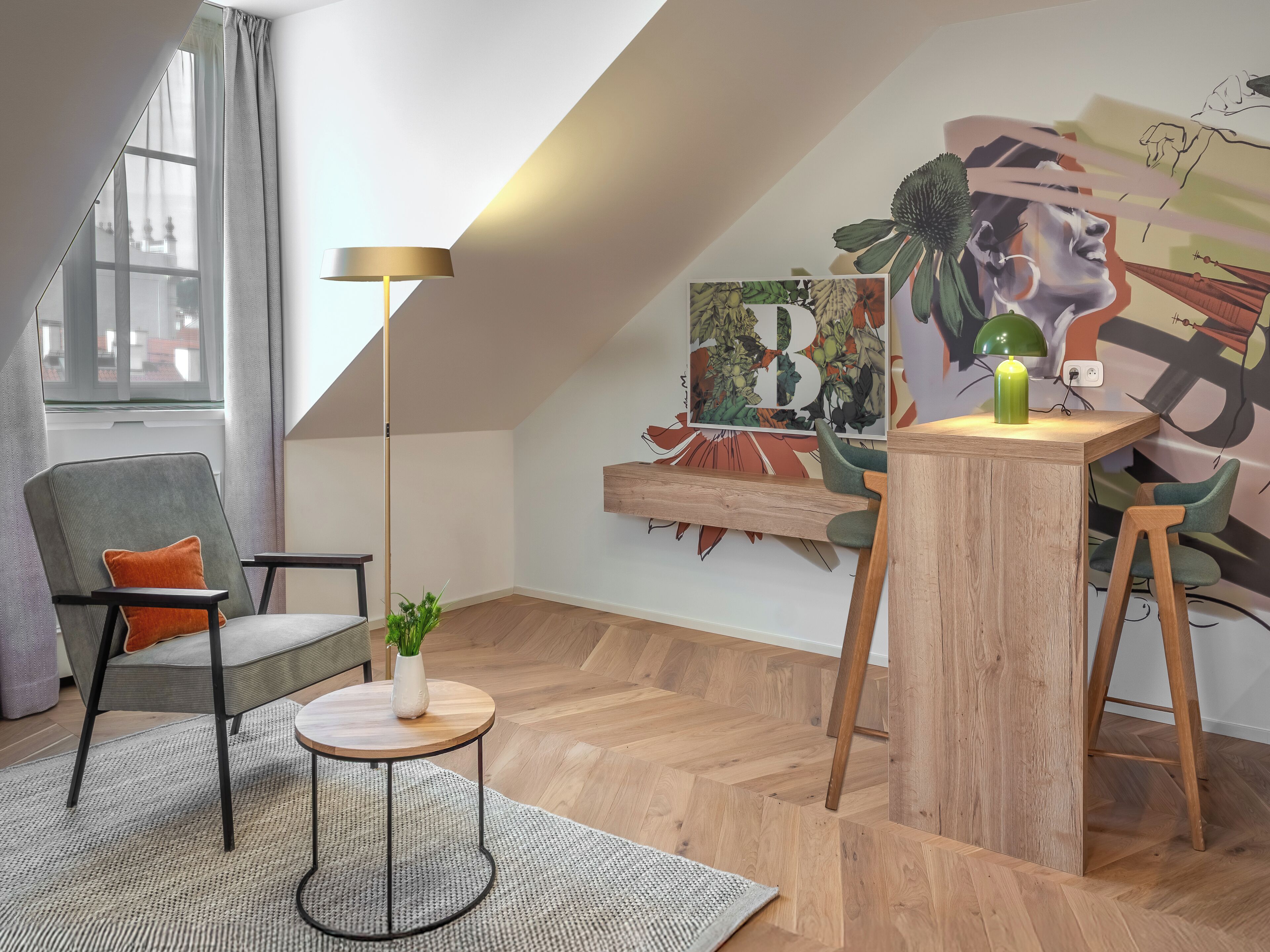 Un dormitorio tipo loft moderno con techo inclinado, un ventanal grande, una planta verde, una mesa redonda de madera y un cuadro abstracto colorido.