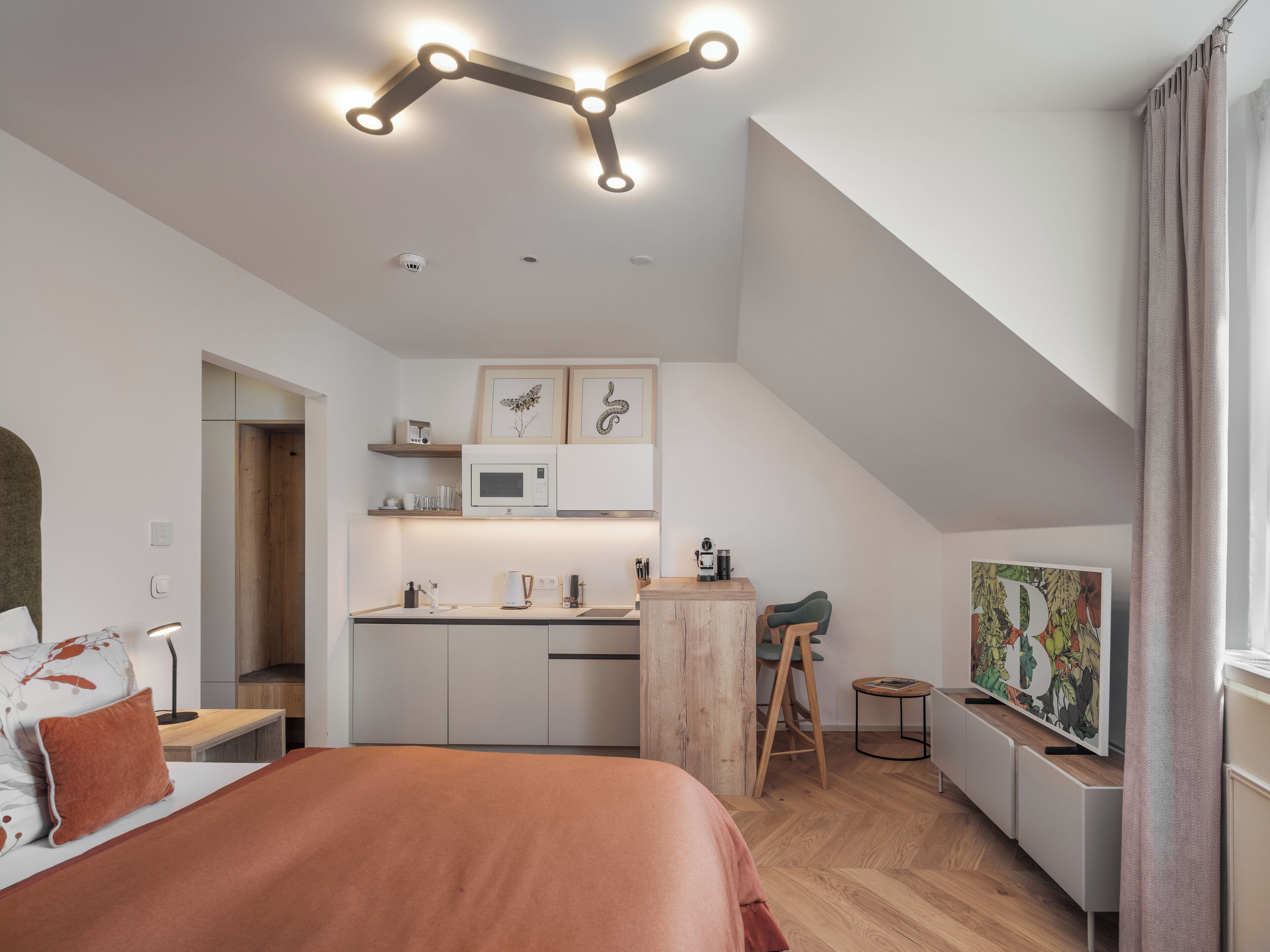 Ein modernes Schlafzimmer mit Bett, Schreibtisch, einer Küchenzeile und einem Schlafbereich auf dem Dachboden.