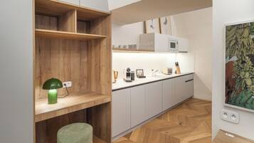 A modern kitchen with wooden shelves, a green lamp, and a herringbone wood floor.