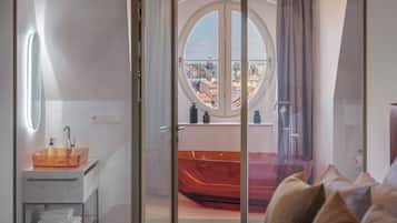 Une chambre à coucher avec un lit, une salle de bain avec une baignoire et une vue sur la ville par la fenêtre.