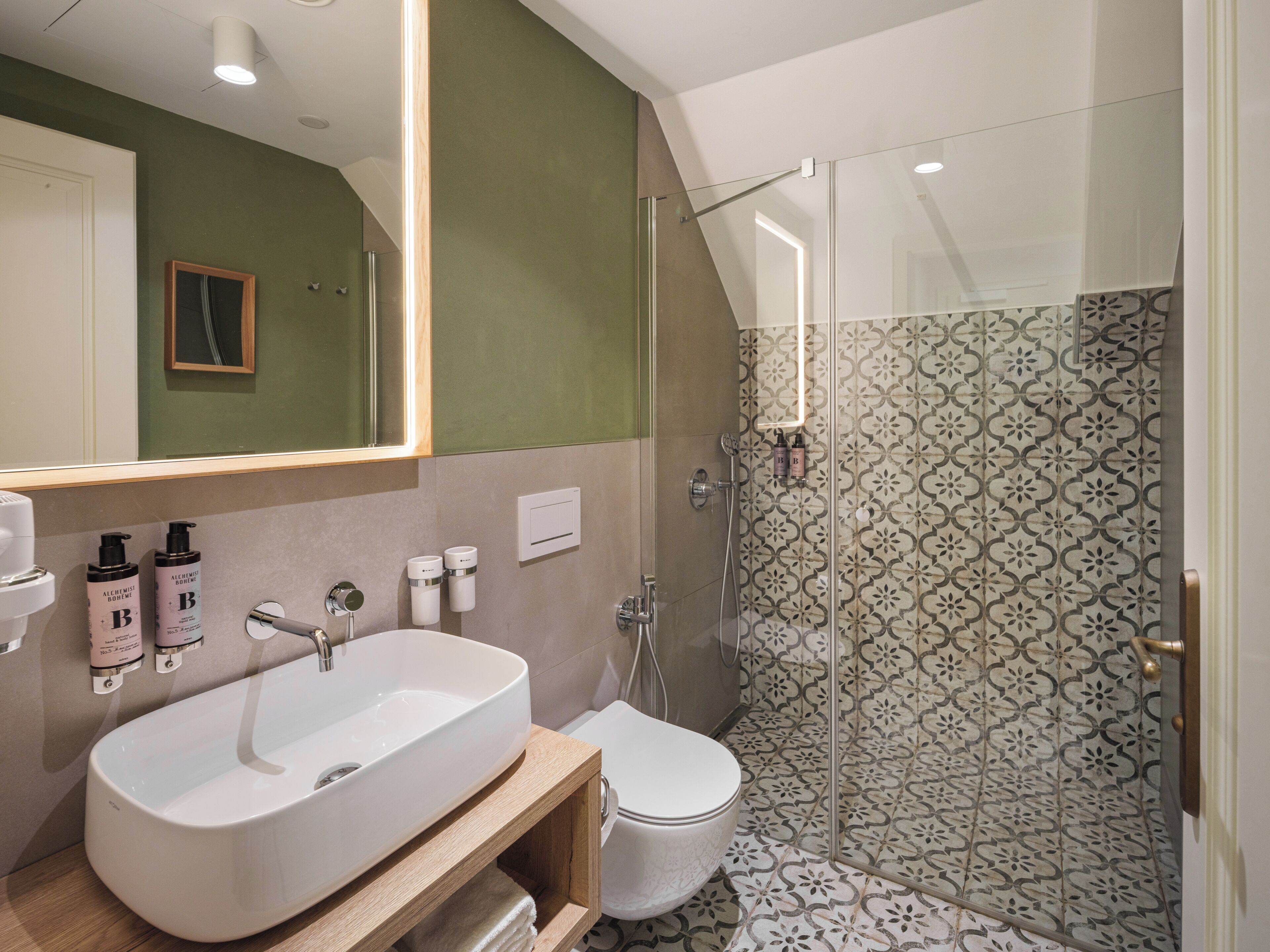 A bathroom with a large mirror, a sink, a toilet, and a shower area.