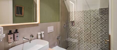A bathroom with a large mirror, a sink, a toilet, and a shower area.