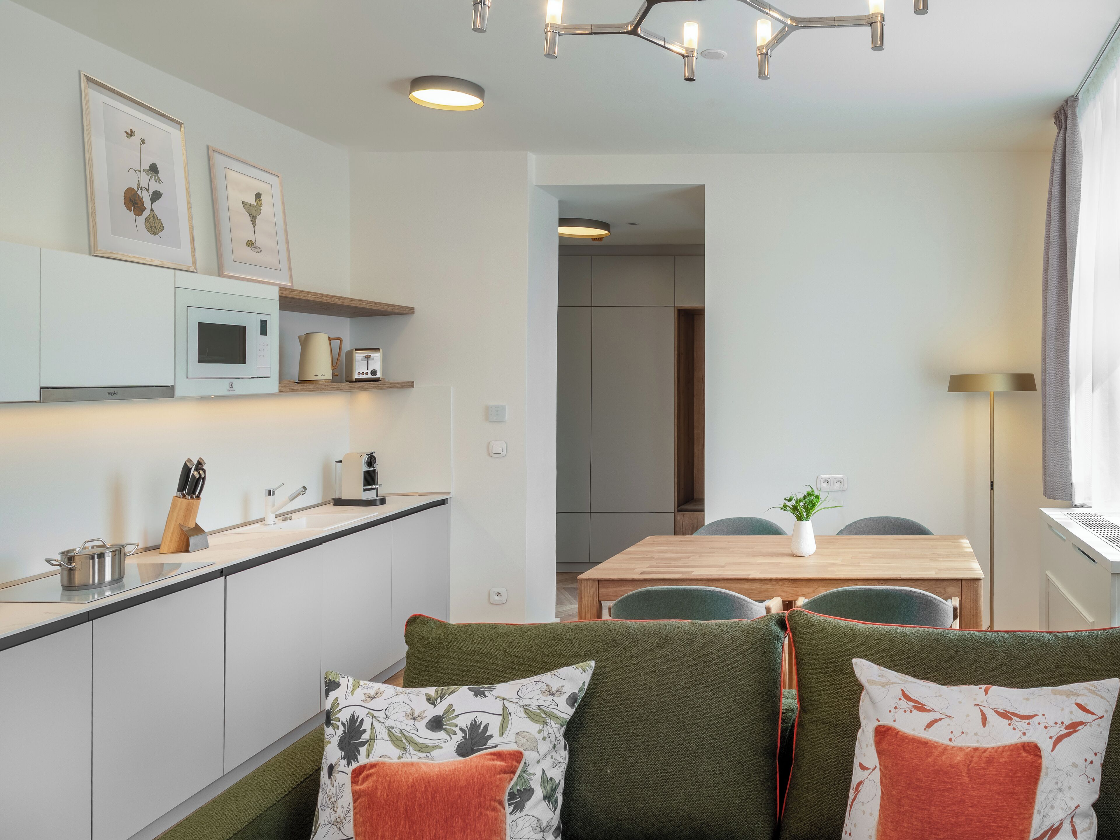 Cocina moderna con microondas, tostadora y cafetera. Hay un comedor con mesa y sillas.