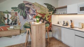 A modern kitchen with a wooden dining table, two chairs, a green plant, and a microwave above the counter.
