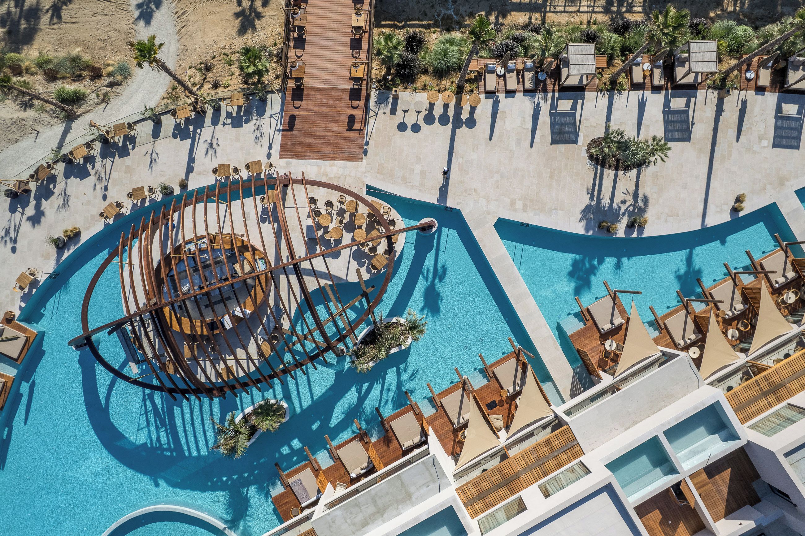 A resort with a large pool, sun loungers, and a wooden deck.