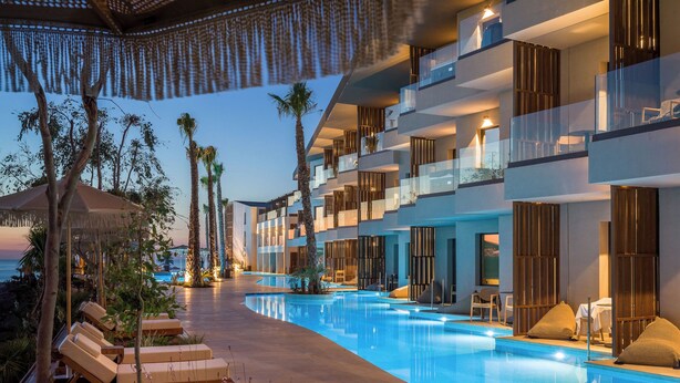Ein modernes Hotel mit Pool, Palmen und Liegestühlen.