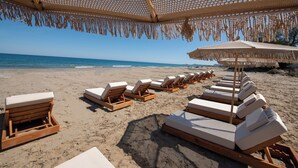 Eine Strandlounge mit Holzliegen und Reetdachschirmen.