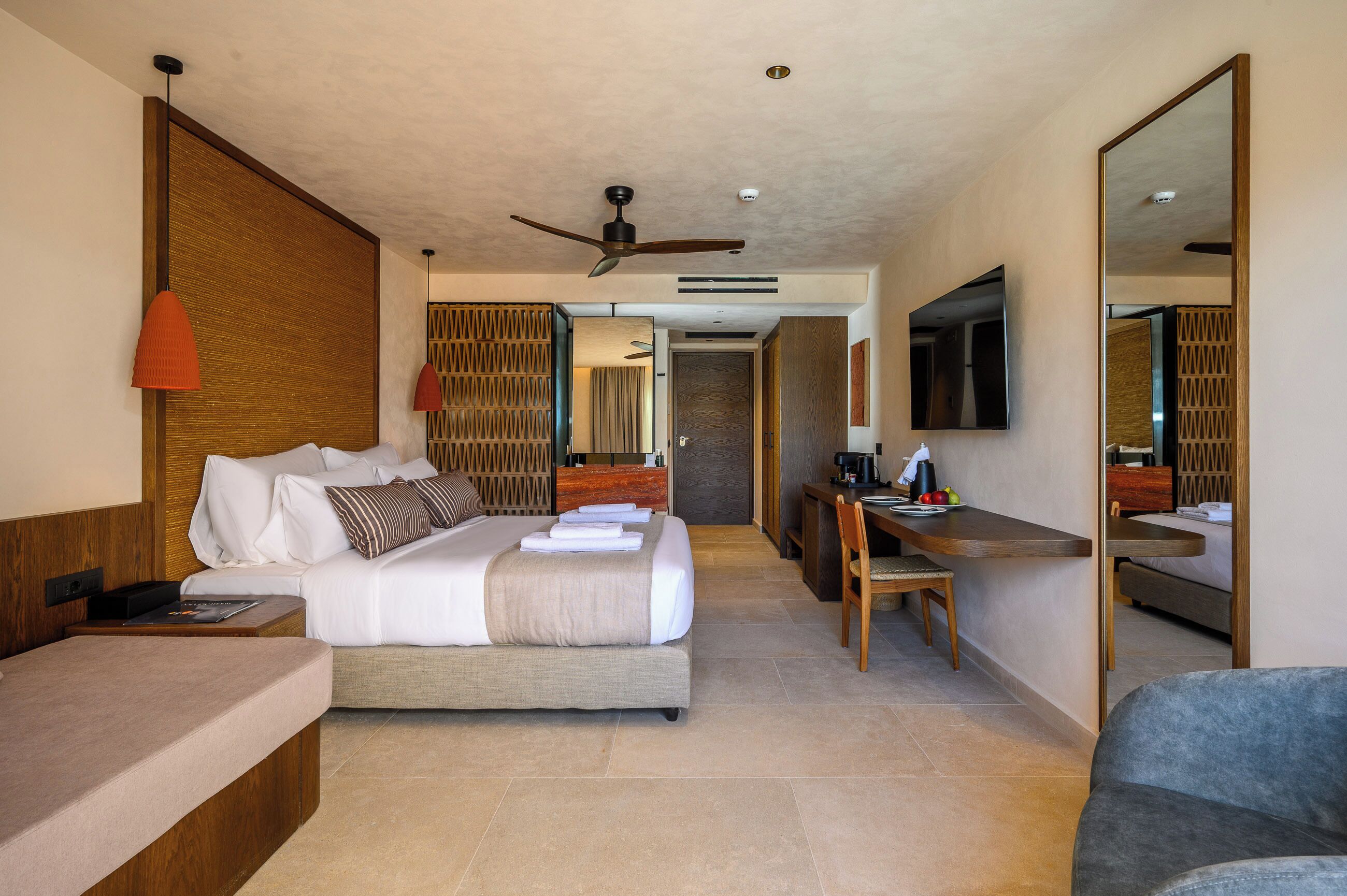 Habitación de hotel con cama, escritorio, silla y un espejo grande.