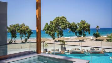 Zona junto a la piscina con vista al mar, sillas de descanso y sombrillas.