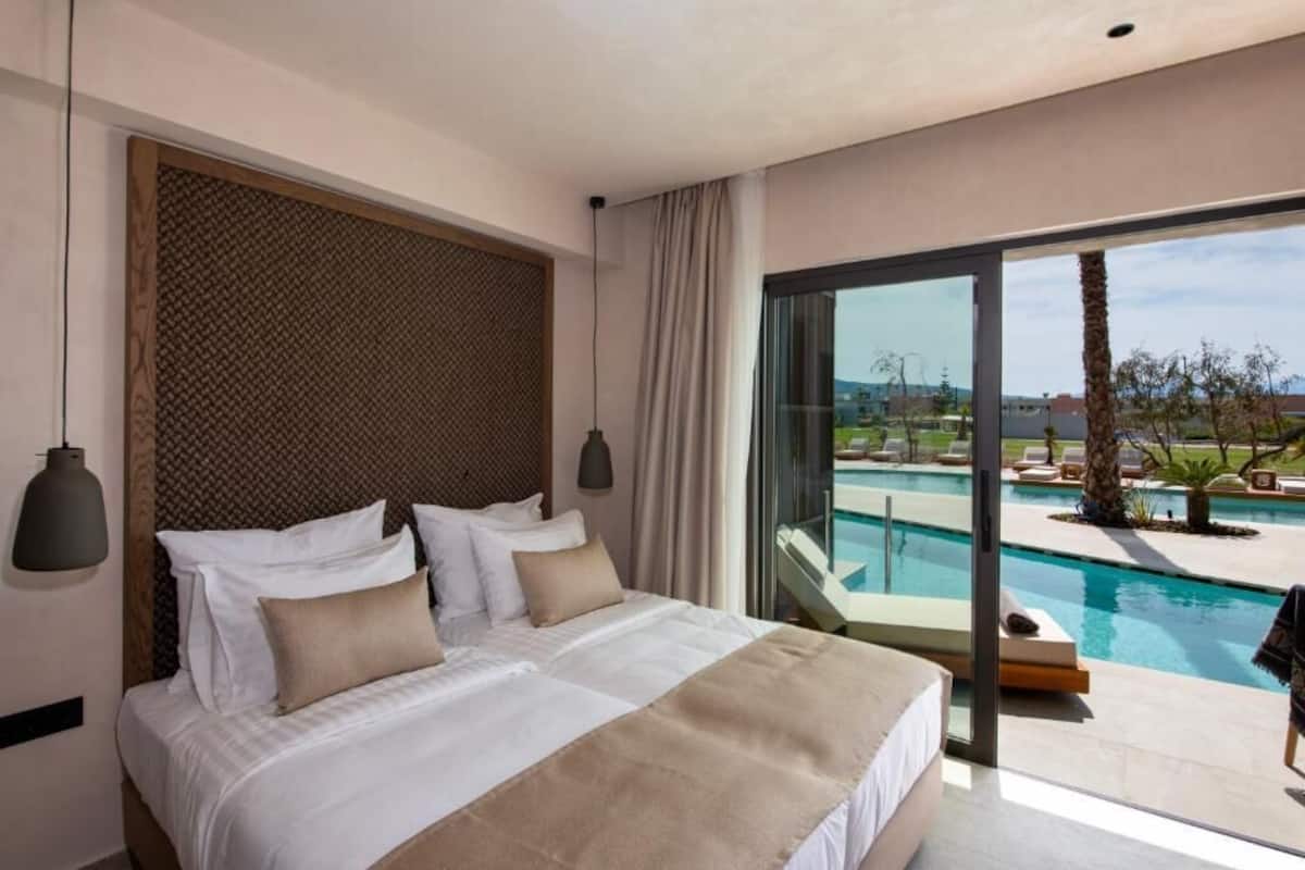 Une chambre d’hôtel moderne avec un grand lit, une vue sur une piscine et un balcon.